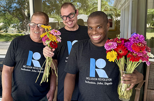 Daniel, Cody, and Kevin smiling together with bouquets on market day